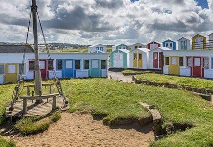 Crooklets Beach, one of the best things to do in Bude, with colourful beach huts, a play area and beachfront cafés
